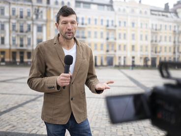 A news reporter getting ready for an interview on a busy street