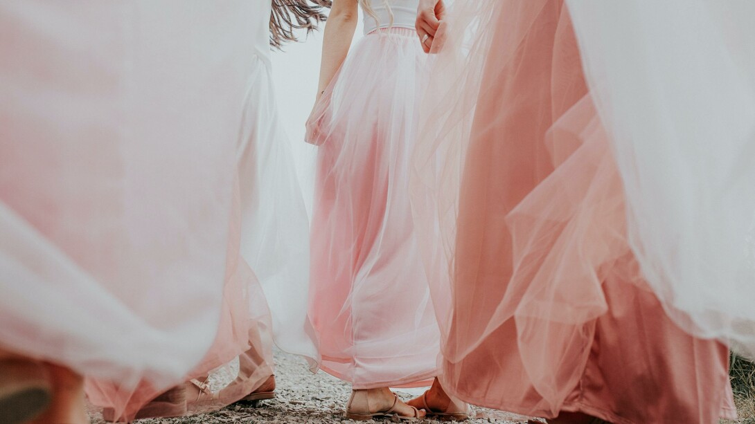 Donne che si tengono la mano in eleganti abiti color cipria 