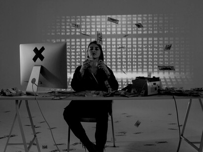 A woman sits at a table piled with money, creating an abstract representation of money laundering