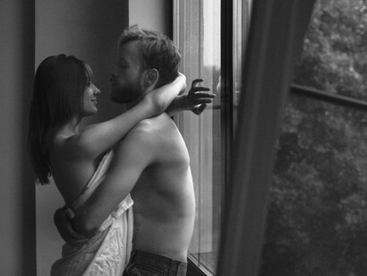 Against the windowpane blurred by rain, two bodies entwine, their touch echoing the tenderness and yearning found in poetry’s most delicate lines
