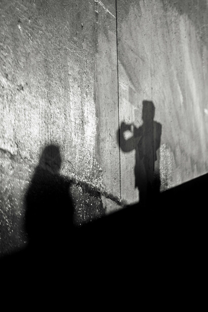 Las sombras se alargan y se deforman en los rincones, doblando la cabeza en la unión de la pared y el techo, como si la arquitectura misma se volviera cómplice del terror