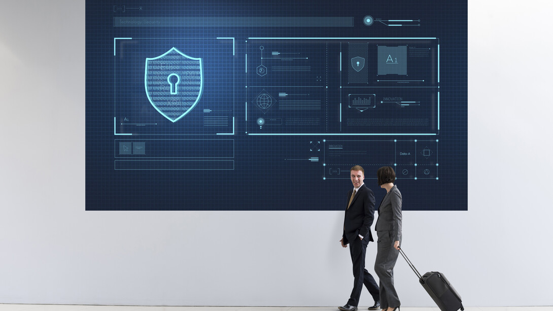 Businesspeople walking by a large cybersecurity advertisement displayed in a modern business area
