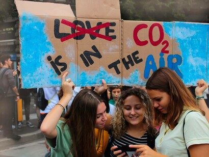 Teenage protestors carrying the sign that scratches out the word 'love' and reads "Co2 is in the air" as their way of expressing their displeasure towards the current climate crisis