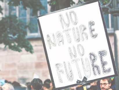 Woman carries a sign to urge mindfulness of climate change