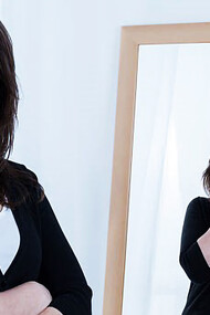 Woman smiling while reflection has hands over face