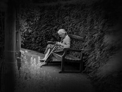 Señora mayor sentada en un banco leyendo