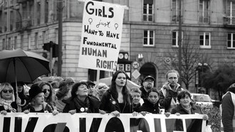 Women march together, proudly holding a banner that reads: "Girls Just Want to Have Fundamental Human Rights