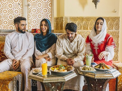 A group gathered around traditional dishes in a Moroccan-inspired interior, symbolising the connection between hospitality, culture, and tourism diplomacy