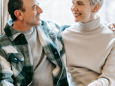 A happy couple relaxing on a couch while enjoying a conversation