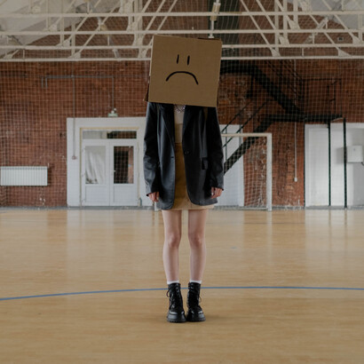 Professora se veste como aluna e coloca caixa de papelão na cabeça com uma carinha triste desenhada