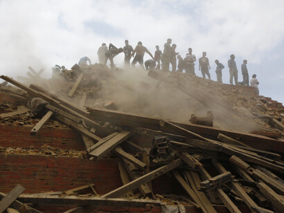 Un grupo de nepalíes trepan sobre un edificio en ruinas para rescatar a una víctima atrapada