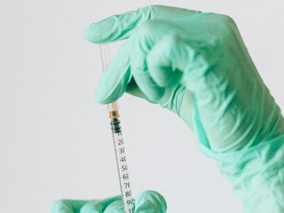 Close-up of a healthcare worker’s gloved hand holding a syringe, ready for vaccination