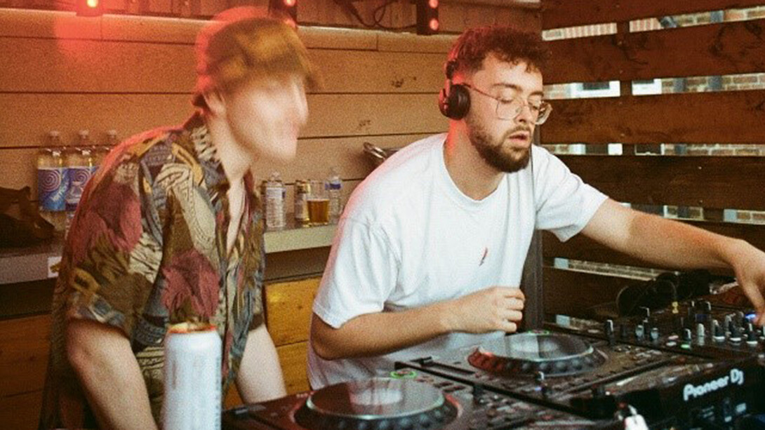 A bespectacled DJ spins mesmerizing beats, while the man beside him dances with unbridledly
