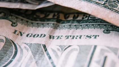Dettaglio di un dollaro con scritto "In God we trust"