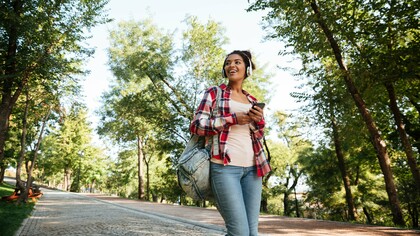 A young woman enjoying a walk, listening to music and smiling at her surroundings