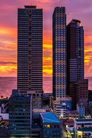 Towering buildings overlooking Manila Bay at dusk, symbolising a city that remains open to history, hope, and endless becoming