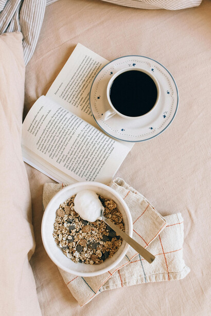Un plato de cereales, un café y un libro sobre una cama