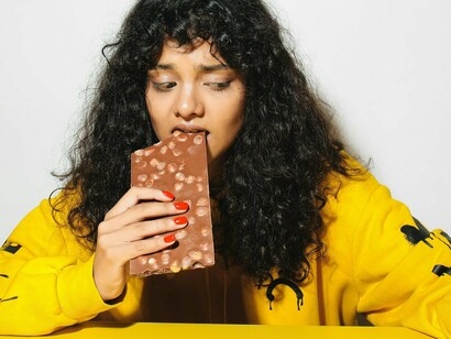 Mulher come chocolate desconfortável. Talvez não seja só distração. Quem sabe prefira ignorar, constrangida demais para enfrentar aquela realidade que destoa de seu mundo polido, ou temendo arruinar o papel de caridosa que desempenha nas campanhas da igreja aos domingos