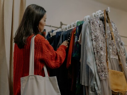 Moça olha roupas em brechó