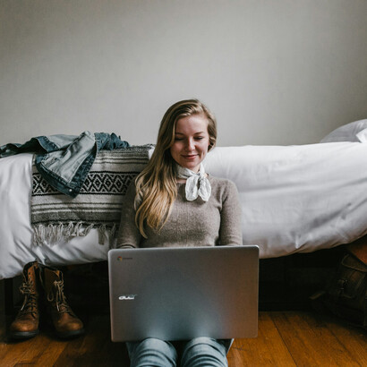 A woman using gadgets in her bedroom; taking technology to bed impairs sleep quality 