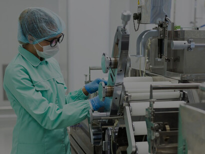 Standing near a manufacturing machine, a scientist in a blue suit represents the seamless integration of food production, processing, and distribution