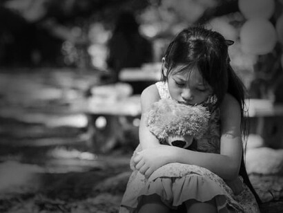 Niña triste abraza un oso de peluche