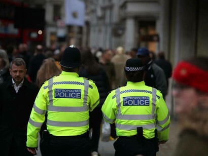 Two police officers in London, England are patrolling the busy streets 