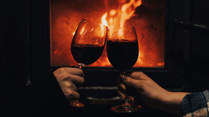 Un brindis con vino tinto en mitad de la noche frente a una chimenea
