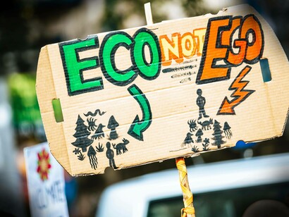 A protest sign reading " eco not ego" with drawings to show that this individual is not in denial of climate change