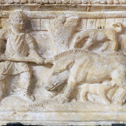 Il cinghiale, anziché incarnare una minaccia cieca, si rivela una creatura cosciente e parlante, capace di osservare e giudicare il comportamento umano. Urnette in alabastro di produzione volterrana con caccia al cinghiale, del 110 a. C. 
