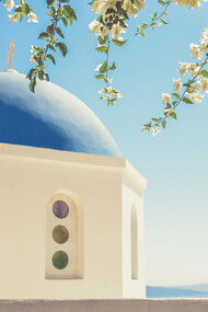 White and blue Byzantine church, with its iconic Greek dome peeking through the lush branches of a tree, Greece