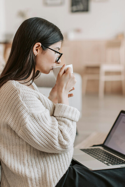 A concentrated female writer typing on her laptop while sitting on the floor in the living room
