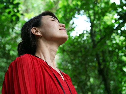 A woman enjoys the fresh air and listens peacefully to birdsong in the forest