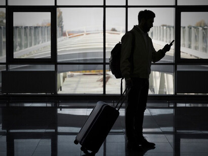A man waits at the airport for his flight, preparing to move abroad for new opportunities