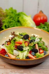A vibrant vegetable salad presented in an earthy brown ceramic bowl