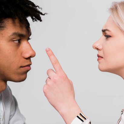 Primo piano di due persone che si guardano da vicino, con una donna che indica verso l'altra persona