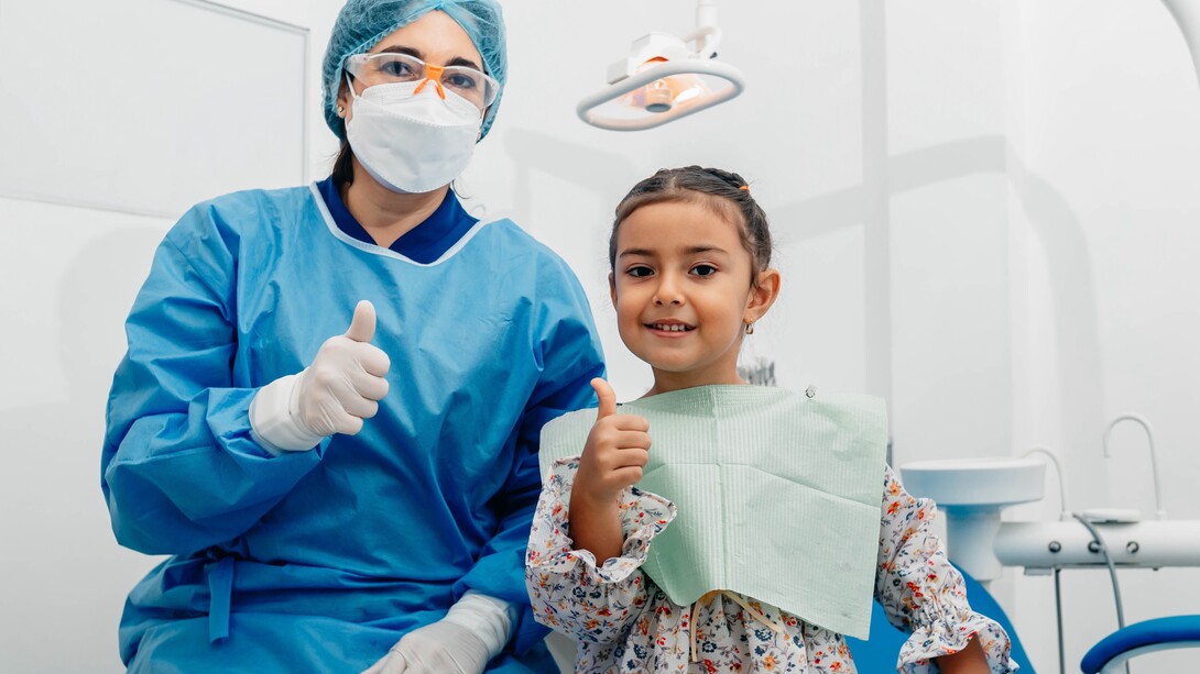 Dentist and young girl give a thumbs-up 