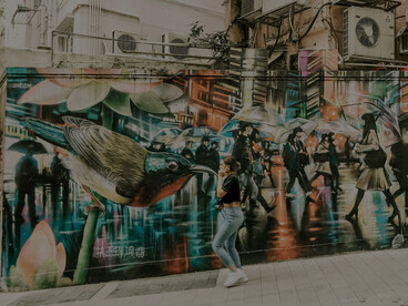 Woman walking past a graffiti-covered wall in Hong Kong