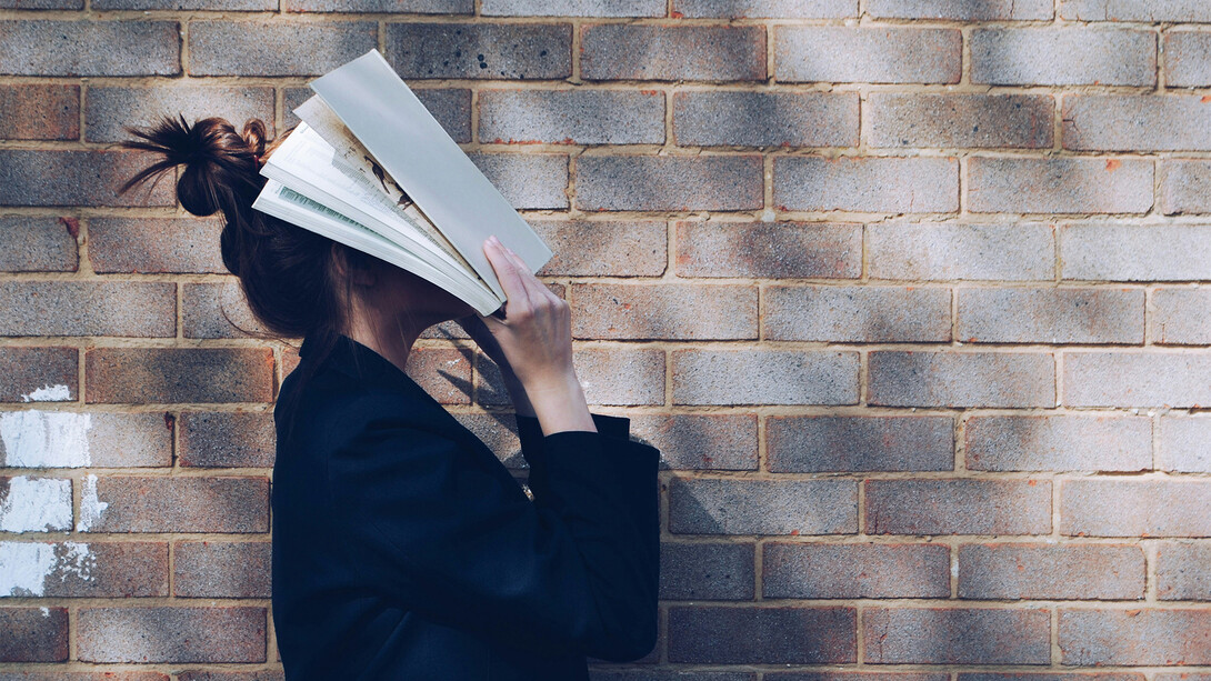 Mulher com livro no rosto. Somos contadores de histórias na nossa própria mente em forma de monólogo