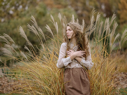 Una ragazza in un campo si lascia cullare dal vento