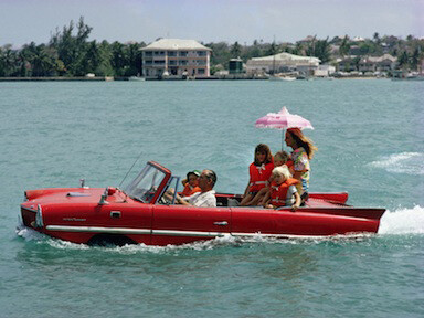 Slim Aarons, Sea Drive, 1967: Film producer Kevin McClory takes his wife Bobo Segrist and their family for a drive in an “Amphicar” across the harbour at Nassau