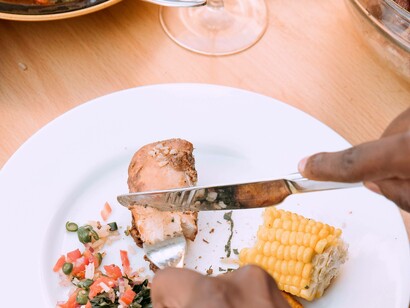 A person cutting off another piece of chicken after being satisfied from the African cuisine