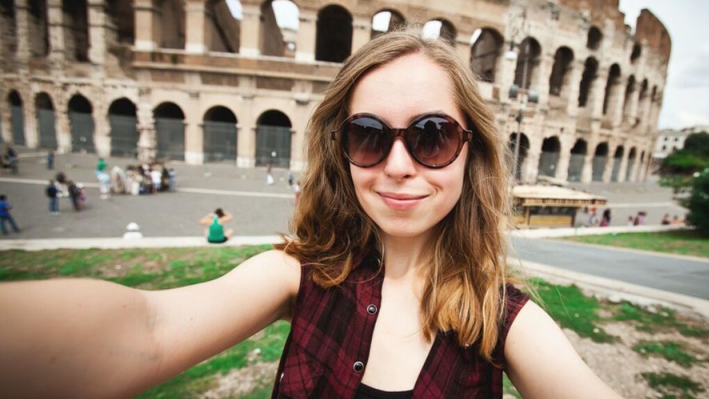 Una turista tomándose una autofoto delante del Coliseo en Roma