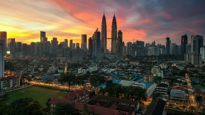 A captivating aerial view of Kuala Lumpur, Malaysia, at sunset, showcasing the city's blend of modern skyscrapers and traditional neighborhoods