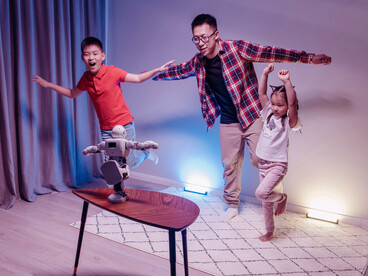 A family dancing together while watching a robot
