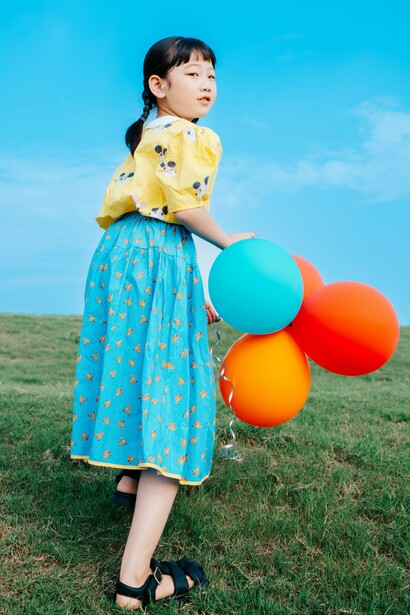 A young girl holding tightly to several balloons as she stands alone, representing the instinct to cling to what makes us feel safe