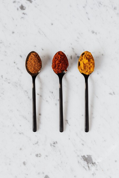 Diversas especiarias secas multicoloridas em colheres na mesa