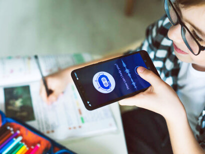 A smiling boy uses an AI chatbot on his mobile app, engaging in a conversation powered by advanced artificial intelligence technology, showcasing the capabilities of virtual assistants in the digital age