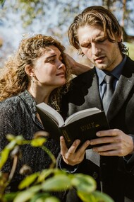 A grieving woman over the loss of a loved one on the shoulders of a priest