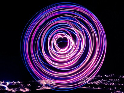 Círculos de luz atravessam a escuridão como reflexos difusos e instáveis. A imagem ecoa a sensação de incerteza e fragmentação presente na análise política do artigo